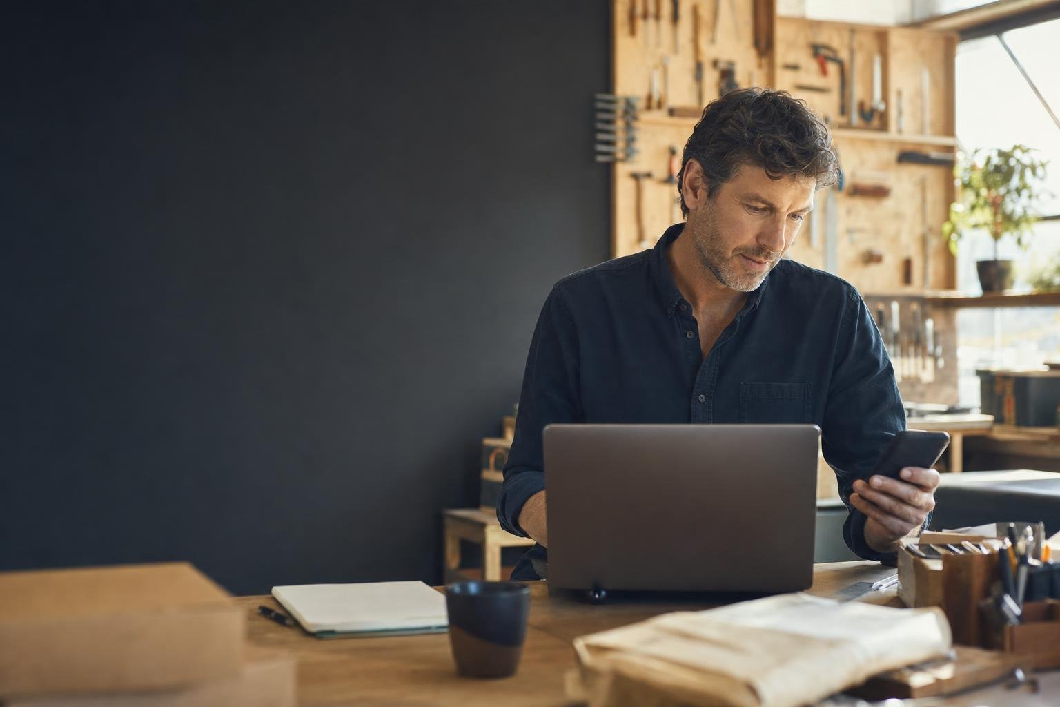 Small business owner preparing for the day with a laptop and phone